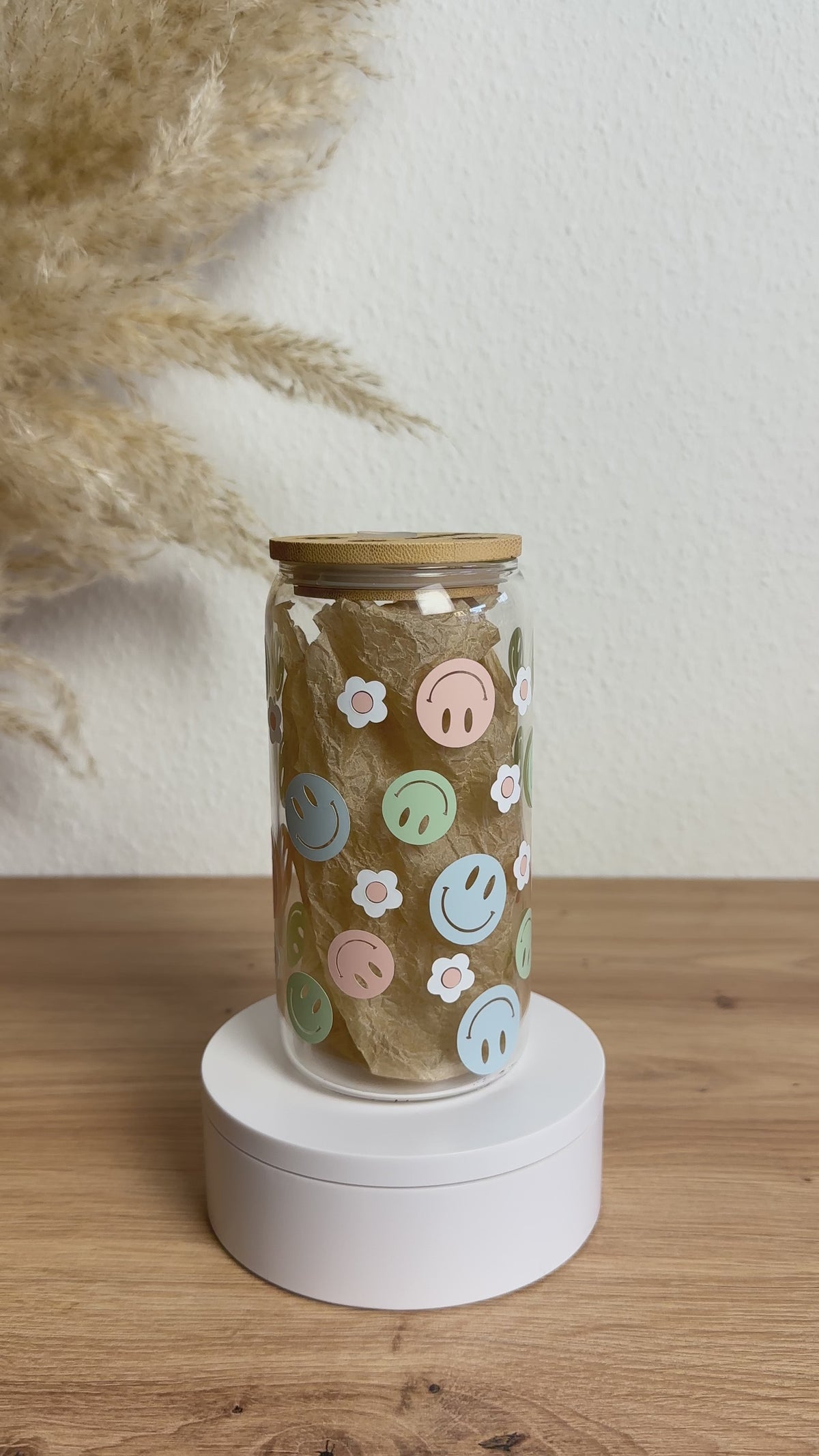 Glasbecher mit Smiley-Blumen-Design in bunten Pastelltönen, Bambusdeckel und Glasstrohhalm, 500 ml nachhaltiger Trinkbecher von Momentwerk Studio in der Rundum-Ansicht