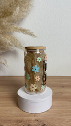 Glasbecher mit MAMA-Design und bunten Blumen, Bambusdeckel und Glasstrohhalm, 500 ml nachhaltiger Trinkbecher von Momentwerk Studio in der Rundum-Ansicht