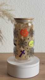 Video eines Glasbechers mit Halloween-Spinnennetz-Design ohne Strohhalm und mit Bambusdeckel auf weißem Sockel, 500 ml Kaffeeglas von Momentwerk Studio
